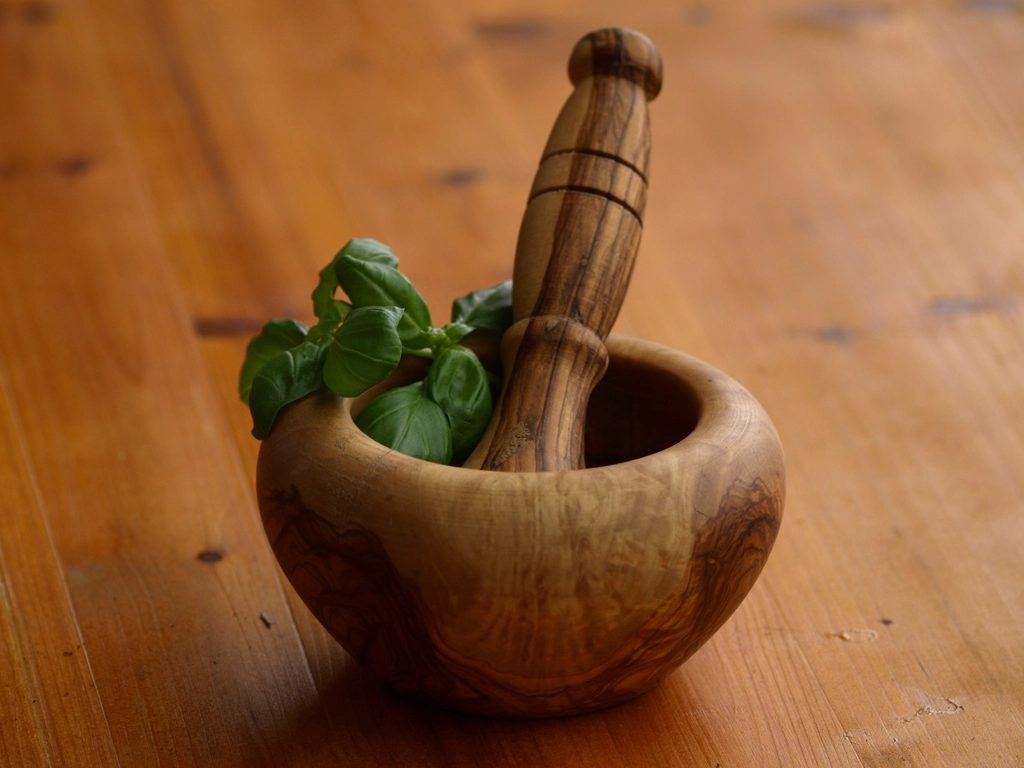 Mortero de madera con hierbas frescas